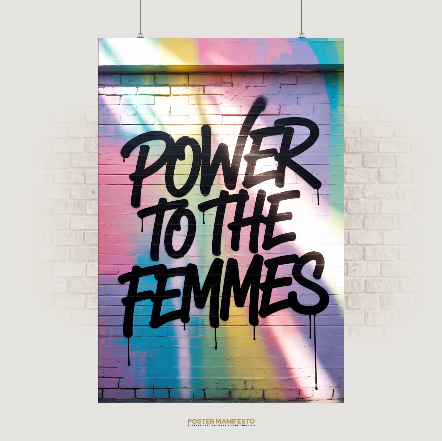 Graffiti text “Power to the Femmes” on pastel spray-painted brick wall