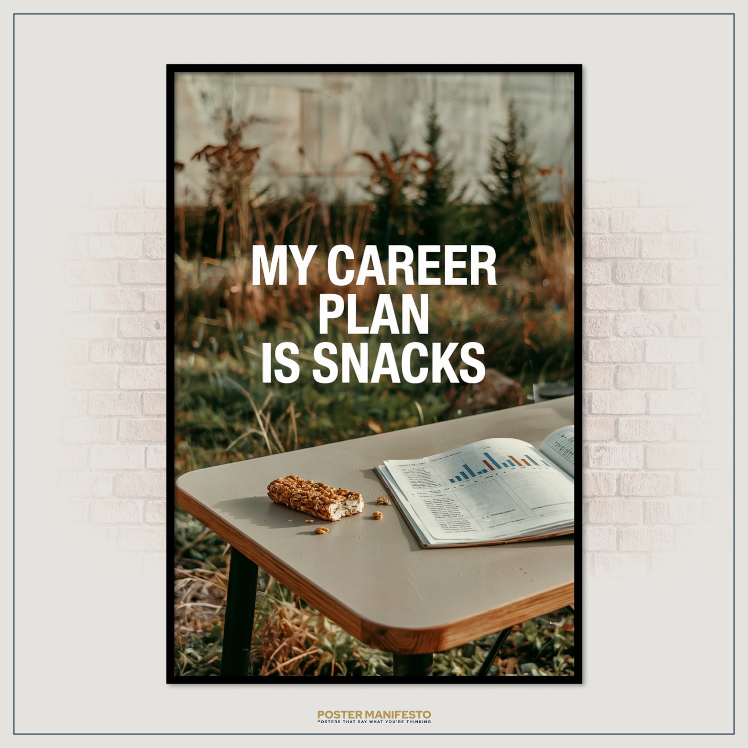 Framed poster with 'My Career Plan is Snacks' text on a table with snacks and a magazine against a brick wall.